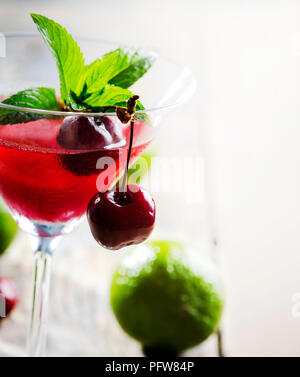 Iced cherry Cocktail in Martini Glas mit Kalk auf Holztisch. Stockfoto