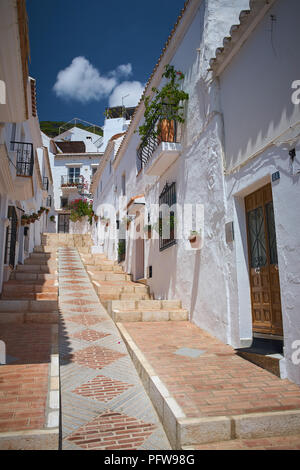 Wandern auf einem steilen engen Spanischen Straße der Weißen gemauerten Häuser in Mijas, Andalusien im Süden Spaniens mit einem blauen Himmel und terracotta-Farben Stockfoto