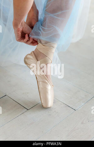 Schöne Beine von jungen Ballerina, die auf Pointe Shoes am weißen Holzboden Hintergrund setzt, Draufsicht von oben mit kopieren. Ballett üben. Bea Stockfoto