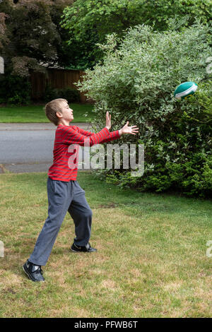 10 Jahre alten Jungen, die versuchen, einen Fußball zu fangen Stockfoto