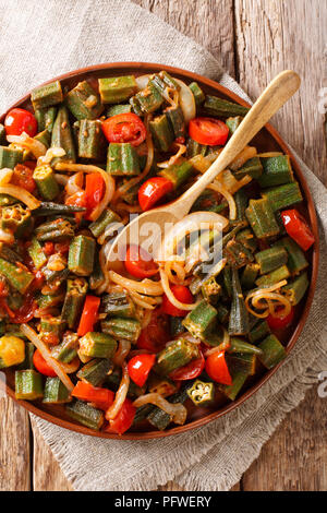 Fried Okra mit Tomaten und Zwiebeln close-up auf einem Teller auf den Tisch. Vertikal oben Ansicht von oben Stockfoto