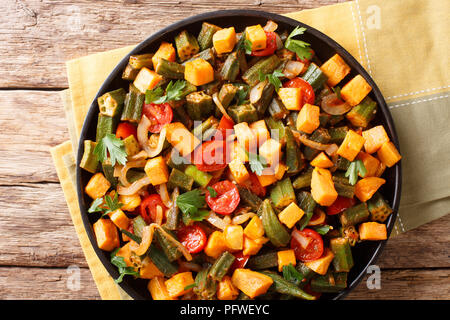 Organische Gesundheit Essen gekocht okra, süße Kartoffeln, Tomaten, Zwiebeln und Kräutern closeup auf einem Teller auf den Tisch. Horizontal oben Ansicht von oben Stockfoto