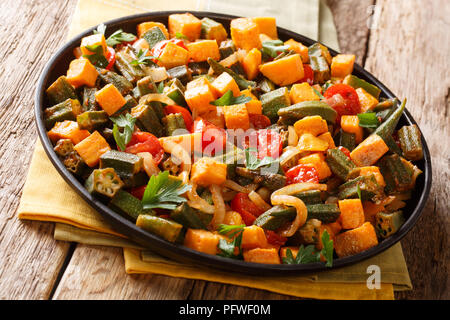 Traditionelles Rezept Ragout von okra, süße Kartoffeln, Tomaten, Zwiebeln und Kräutern close-up auf einem Teller auf dem Tisch. Horizontale Stockfoto