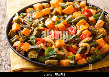 Organische Gesundheit Essen gekocht okra, süße Kartoffeln, Tomaten, Zwiebeln und Kräutern closeup auf einem Teller auf den Tisch. Horizontale Stockfoto