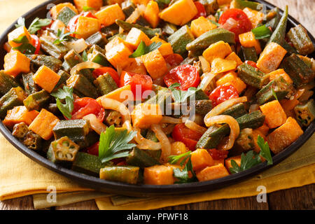 Lecker Gemüse okra, süße Kartoffeln, Tomaten, Zwiebeln und Kräutern closeup auf einem Teller auf den Tisch. Horizontale Stockfoto