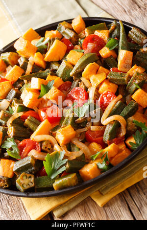 Gemüseeintopf okra, süße Kartoffeln, Tomaten, Zwiebeln und Kräutern closeup auf einem Teller auf den Tisch. Vertikale Stockfoto