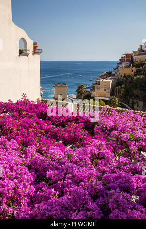 Positano durch rosafarbene Bougainvillea und Boote im Hintergrund eingerahmt. Bunte Positano, das Juwel der Amalfi Küste, mit seinen bunten Häusern und Stockfoto