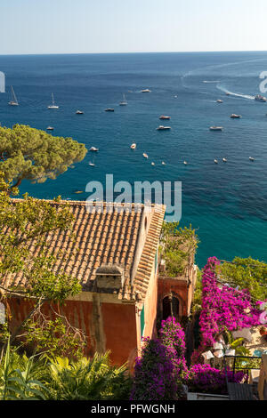 Positano durch rosafarbene Bougainvillea und Boote im Hintergrund eingerahmt. Bunte Positano, das Juwel der Amalfi Küste, mit seinen bunten Häusern und Stockfoto