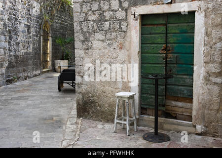 Eine Tür mit einem Stuhl und ein Tisch auf einer Straße in Kotor, Montenegro Stockfoto