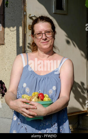 Lächelnde Frau mit Schale, frisch gepflückte Früchte und Gemüse aus dem Garten zala Ungarn Stockfoto