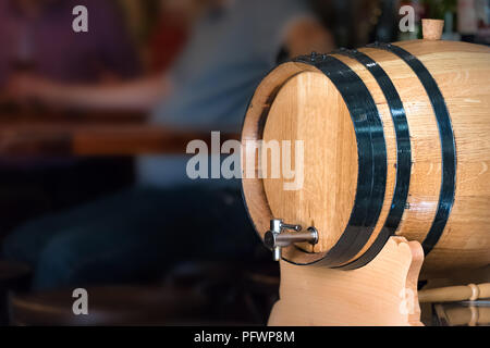 Eine kleine Wein - Bier Holzfass platziert im Freien eine Bar mit unscharfen Menschen als Hintergrund. Stockfoto