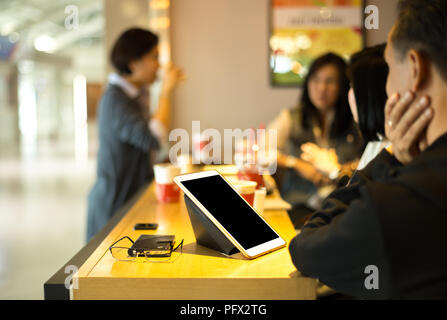 Ausgewählte Schwerpunkte Tablet und Gläser auf dem Tisch mit einer Gruppe von Fr Stockfoto