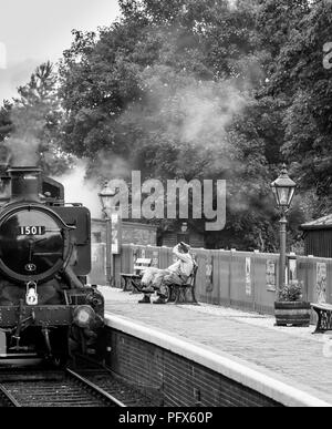 Schwarz-weiße britische Dampfmaschinenbesatzung, die eine kurze Pause außerhalb des Fahrerhauses machte, Severn Valley Railway Arley Station. Vorderansicht der Loco 1501-Dampfgarung. Stockfoto