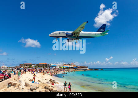 Eine Jetblue Flug geht über Maho Beach und Dutzende Touristen kurz vor der Landung am Princess Juliana International Airport in Saint Martin. Stockfoto