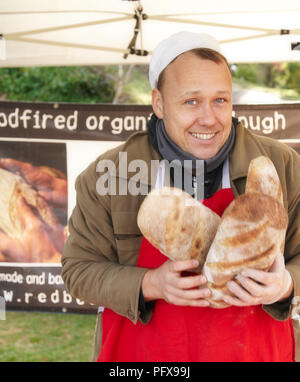 Ein Bäcker hält Brote aus frisch gebackenen organische Sauerteigbrot. Stockfoto