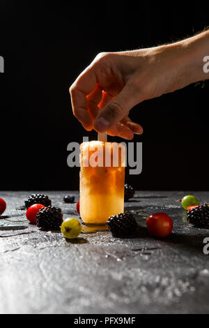 Foto oben von gefrorenem Obst Saft, der menschlichen Hand und Beeren Stockfoto