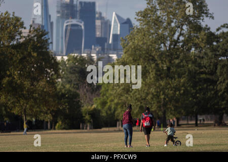 Eine Familie Spaziergang durch Ruskin Park und die Skyline der Stadt von Londons Finanzviertel, am 8. August 2018, in London, England. Stockfoto