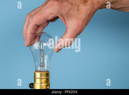 Ältere Menschen Hand herausdrehen der Halogenlampe Stockfoto