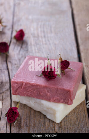 Natürliche handgemachte Seife mit trockenen Rosen auf vintage Holz- Hintergrund spa Einstellung Stockfoto