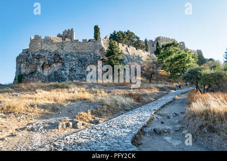 Dies ist der alte Stein Straße, die Kurven es weg bis zu der Akropolis in Lindos auf der griechischen Insel Rhodos. Esel nehmen Menschen das Schloss Stockfoto