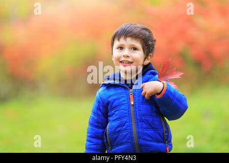 Junge mit einem roten Ahornblatt im Herzen der Region mit großem Stolz als kanadischer Bürger. Portrait von kleinen weissen Kaukasischen boy Holding Herbst lea Stockfoto