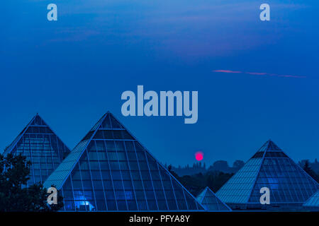 Sun steigt durch Rauch Himmel, Muttart Conservatory Pyramiden, Edmonton, Alberta, Kanada. Stockfoto