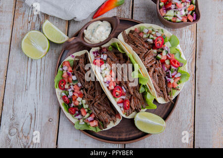 Mexikanische Tacos mit gebratenem Rindfleisch, Soße und salsa Tomaten Stockfoto