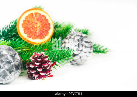 Tannenzweigen auf Weiß mit Zitrusfrüchten getrockneten Scheiben und Silber Zinn Kugeln dekoriert. Weihnachtsdekoration. Stockfoto