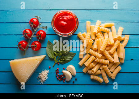 Pasta mit verschiedenen Zutaten zum Kochen Italienische Küche, auf einer blauen Tabelle Stockfoto