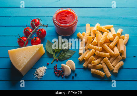 Pasta mit verschiedenen Zutaten zum Kochen Italienische Küche, auf einer blauen Tabelle Stockfoto