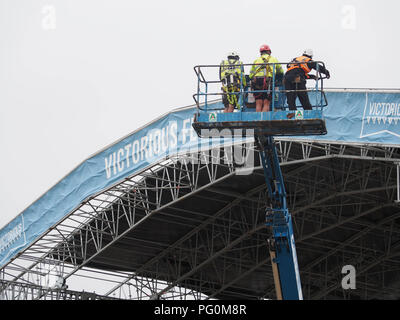 Stage crew errcting eine Bühne für ein Musikfestival mit einem Cherry Picker Stockfoto