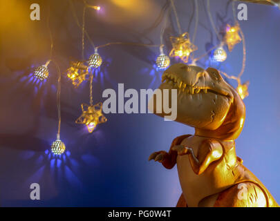 Spielzeug Szene - Butch das lächelnde Dinosaurier gegen eine festliche Sternenhimmel blauen Hintergrund. Stockfoto