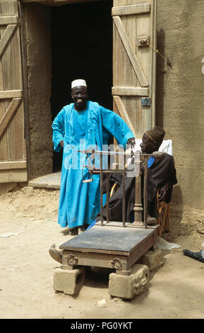 Mann mit Türkis Roben beobachten die Skalen in Djenne, Mali für redaktionelle NUR VERWENDEN Stockfoto