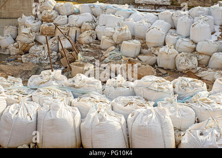 Viele große weiße Sandsäcke für Hochwasserschutz. Stockfoto