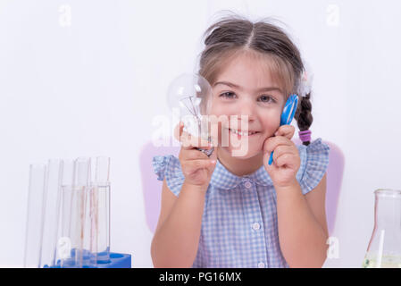 Süße kleine Mädchen mit Funny Face in Schuluniform hält Lupe und Glühlampe. selektive Fokus und und Konzept Bild Stockfoto