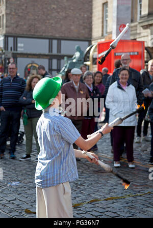 Edinburgh, Schottland, Großbritannien, 23. August 2018. Edinburgh Fringe Festival, Royal Mile, der 12 Jahre alte Patrick aus Edinburgh spielt mit dem Feuer mit seinem Balanceakt erscheinen an seinem ersten Fringe als strassenmusikant. Stockfoto