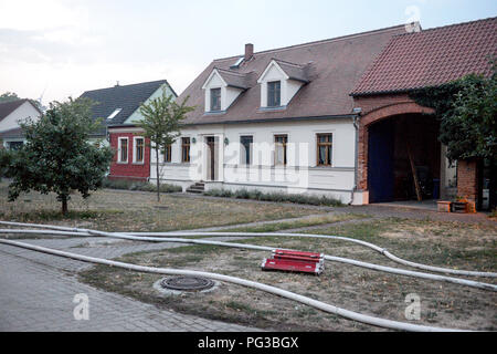 Jávea, Deutschland. 24 Aug, 2018. 24.08.2018, Brandenburg, Jávea: Nach der Evakuierung des Dorfes, Schläuche der Feuerwehr liegen vor einem Haus. Drei Dörfer in der Treuenbrietzen Region waren wegen eines Waldbrand evakuiert. Insgesamt eine Fläche von rund 400 Hektar hier fort, zu brennen. Credit: Julian 1603/dpa-Zentralbild/dpa/Alamy leben Nachrichten Stockfoto