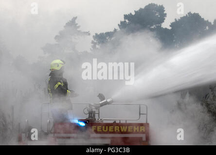 Treuenbrietzen, Deutschland. 24 Aug, 2018. Ein Feuerwehrmann löscht ein Feuer in einem riesigen Wald Feuer in Treuenbrietzen. Drei Dörfer in der Region wurden evakuiert. Insgesamt eine Fläche von rund 400 Hektar weiter zu brennen. Quelle: Michael Kappeler/dpa/Alamy leben Nachrichten Stockfoto