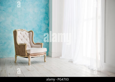 Vintage Sessel gegen weiße Wand und große Fenster mit Vorhang. Platz für Ihre Kopie Stockfoto