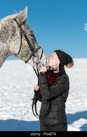 Teenager (14 Jahre) Mädchen mit tschechischen Warmblut Pferd auf Schnee im Winter Stockfoto