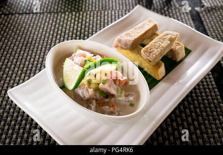 Oka - wie Kokoda, Poke, Ceviche, oder Poisson Cru bekannt - ist im Polynesischen roher Fisch Salat aus Samoa, mit taro Chips in einem Restaurant Stockfoto