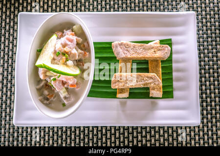 Flach von Oka - wie Kokoda, Poke, Ceviche, oder Poisson Cru bekannt - ist im Polynesischen roher Fisch Salat aus Samoa, mit taro Chips in einem Restaurant Stockfoto