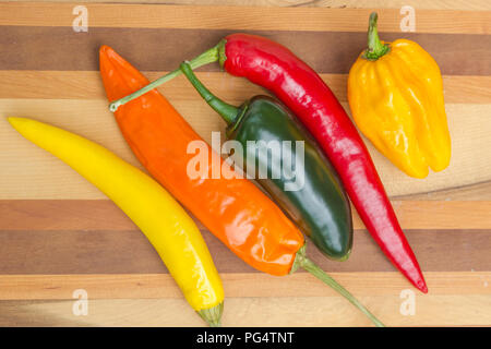 Rot, Grün, Gelb und Orange chilis auf isolierte Holz Hintergrund Stockfoto