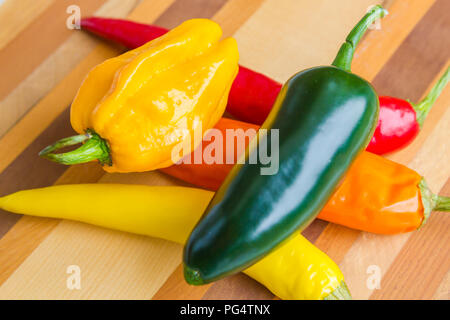 Rot, Grün, Gelb und Orange chilis auf isolierte Holz Hintergrund Stockfoto