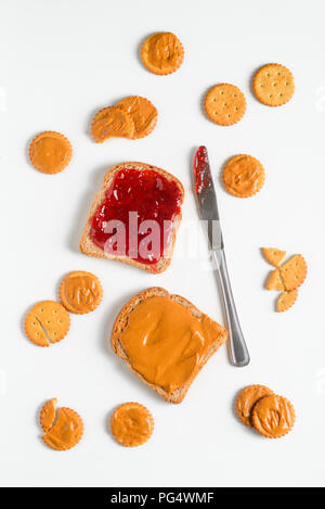 Peanut Butter und Erdbeermarmelade Sandwich, Cracker und Messer, top-Ansicht. Weißer Hintergrund. Stockfoto