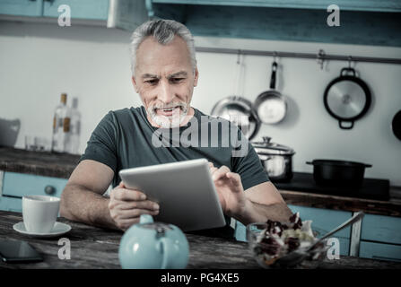 Stattliche reifer Mann in der Küche sitzt Stockfoto