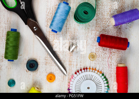 Nähzubehör auf einer hölzernen Hintergrund. Maßband, Pins, Buttons, Reißverschluss, Schere und Faden. Stockfoto