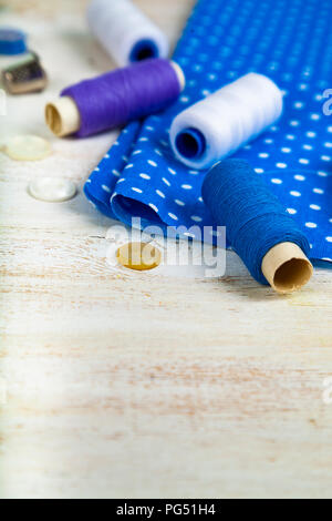 Nähzubehör und blauen Stoff auf einer hölzernen Hintergrund. Stoffen, Maßband, Pins, Buttons und Gewinde. Stockfoto