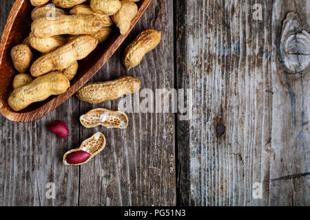 Erdnüsse in eine hölzerne Schüssel auf einen alten Tisch. Leckere und gesunde Nüsse close-up. für ihren Text. Stockfoto