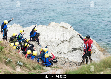 Urlauber Hören zu einem Sicherheit Vortrag von coasteering Instruktoren auf der Landspitze in Newquay, Cornwall. Stockfoto